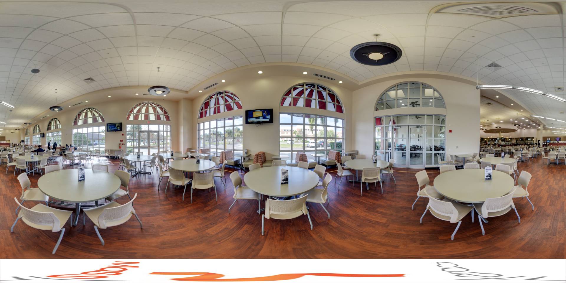 Panoramic view of a spacious cafeteria with arched windows and modern furnishings